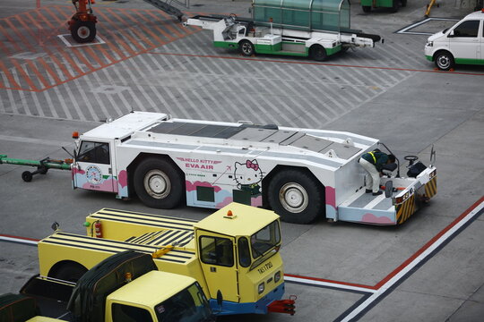 An airport pushback tractor with Hello Kitty livery sits on the tarmac.