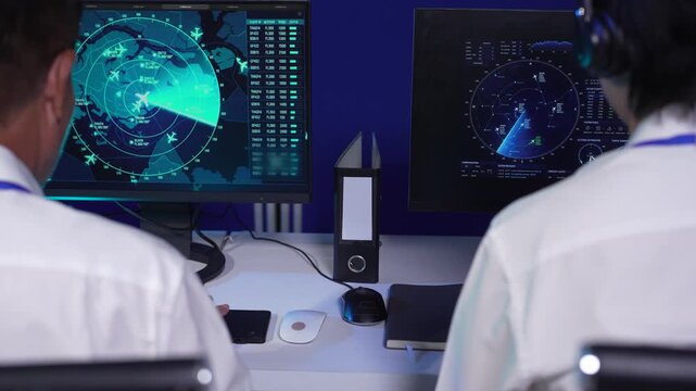 Team air traffic controller working on radar flight tracking screen in control room.