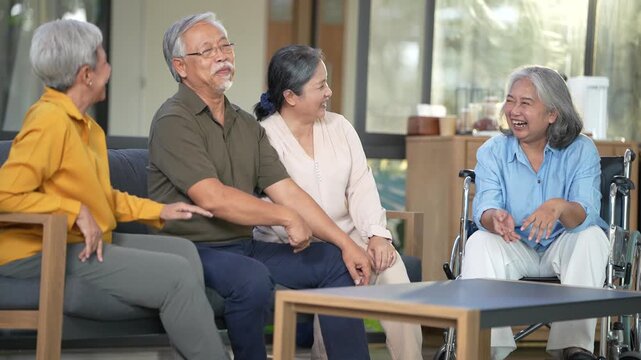 Senior man in an olive shirt stretches an arm along the sofa back while the group swaps stories in the day room. 4K aged-care video suitable for hospital and wellness marketing.