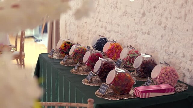 Handheld reveal of colorful candy jars on wedding sweets table.