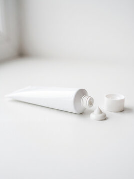 White medical cream tube with small amount of cream, minimal surface, isolated softly blurred white background, skincare and healthcare concept. Close-up.