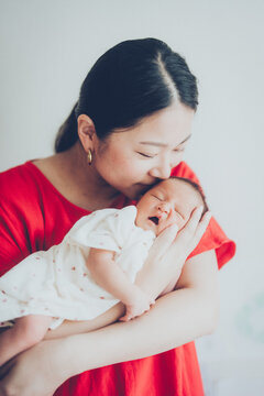 新生児を抱っこしてキスするお母さん
