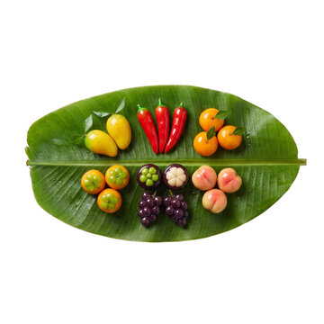 Assorted Thai luk chup fruit shaped desserts on banana leaf isolated on transparent background