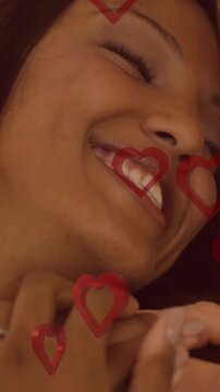 Animation of red hearts over couple in love embracing and smiling