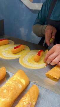 Thai Street Food Vendor Rolling Sausage Crepes on Metal Griddle