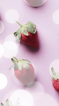 Composition of spots of light over strawberries on pink background