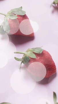 Composition of spots of light over strawberries on pink background