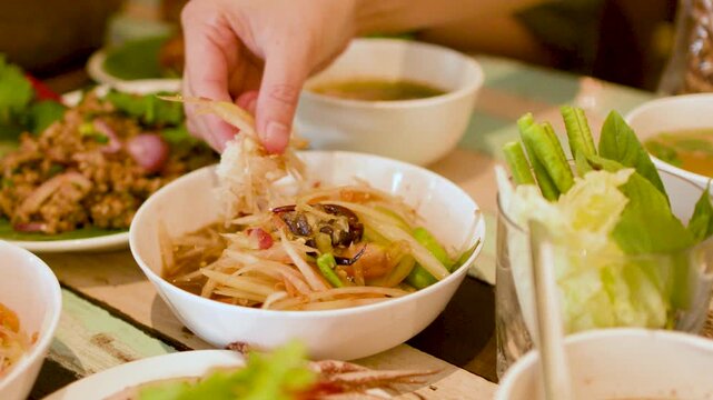 Person Dipping Sticky Rice into Spicy Thai Papaya Salad