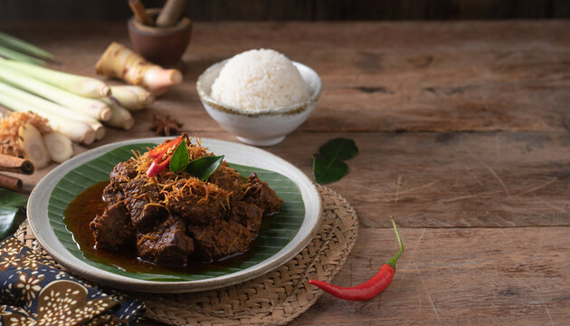 Traditional Indonesian beef rendang served with steamed white rice on a wooden table.