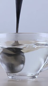 Metal Spoon Stirring Sugar into Hot Water in Glass Cup