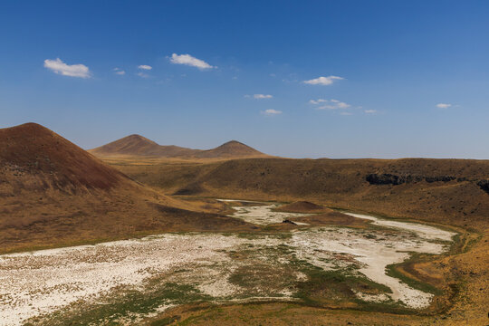 Aerial view of the dry landscape of Meke Lake, a volcanic crater lake in Karapinar, Konya, Turkey, surrounded by barren hills and salt-covered ground.
