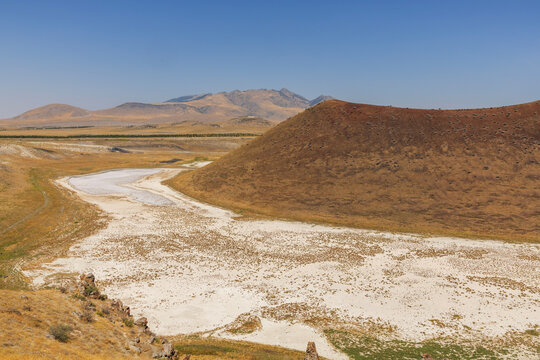 Aerial view of the dry landscape of Meke Lake, a volcanic crater lake in Karapinar, Konya, Turkey, surrounded by barren hills and salt-covered ground.