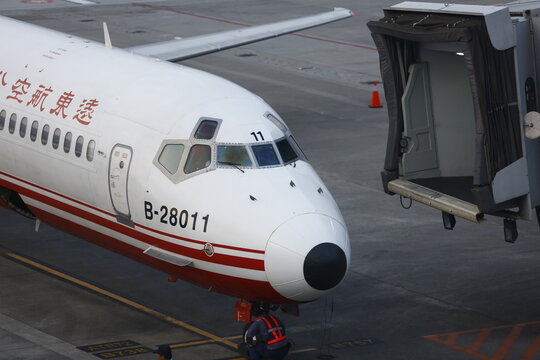 A commercial passenger airplane docks near a jet bridge.