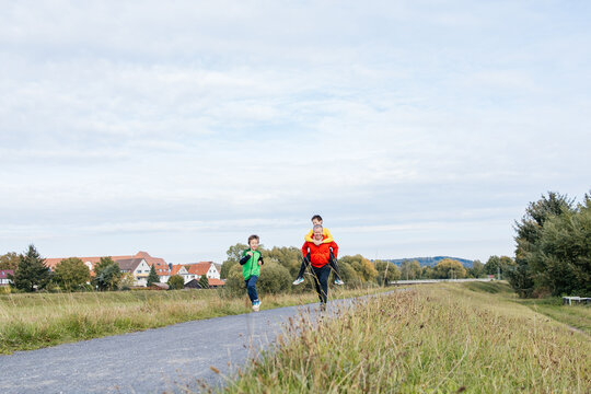 Family running on path with father carrying son piggyback