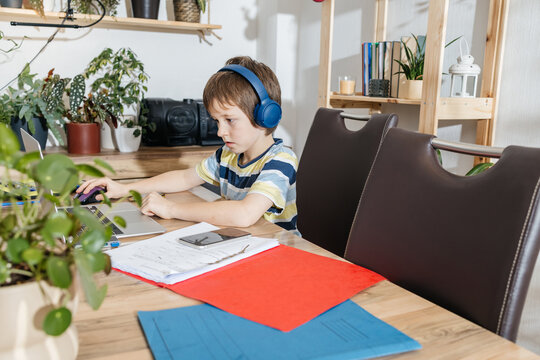 Young boy studying at home using laptop with headphones