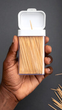 Person Holding Toothpick Dispenser on Grey Background