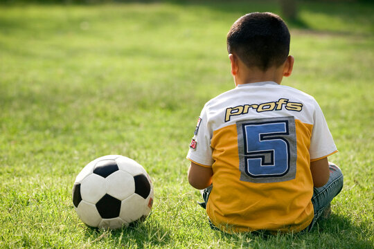 Boy sitting with a football on his side 