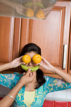 Woman covering her face with fruits 