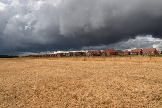 After months of drought in storm clouds gather over a new housing estate  rain relive over due on grass and countryside 