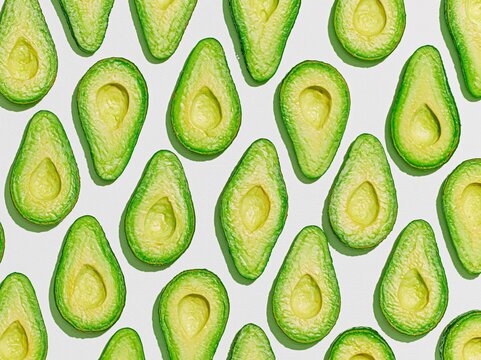 Avocado halves arranged in a repeating pattern on a light background, representing healthy eating