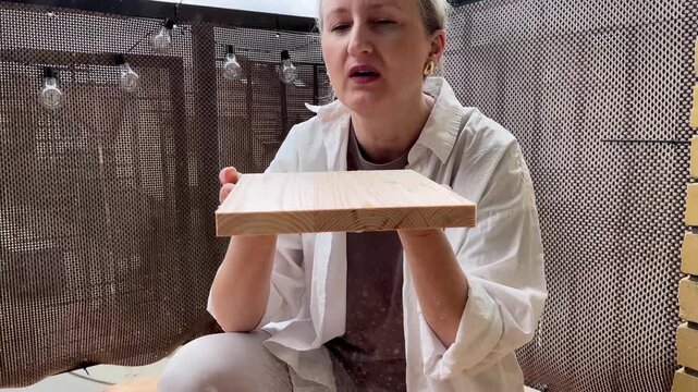Woman blows sawdust off freshly cut wooden board after jigsaw cutting in slow motion 4K. Concept of meticulous woodworking finish and satisfying detail in DIY furniture construction process.