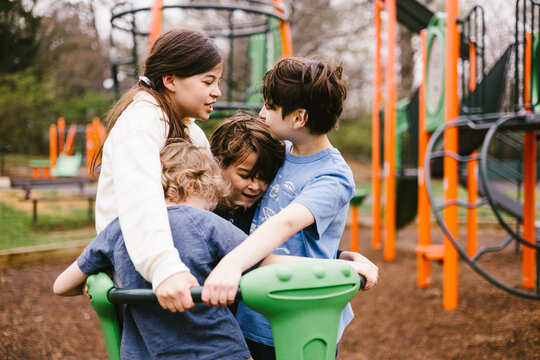 A group of kids playfully huddle on a playground