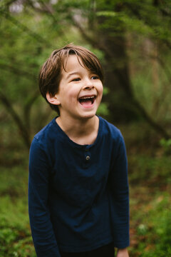 Happy young boy laughing joyfully outside in the woods