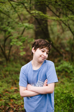 Smirking boy with crossed arms stands outdoors