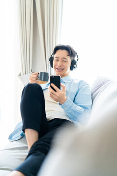 コーヒーを飲みながらスマートフォンを使う男性