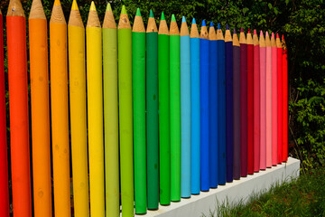 Fototapeta premium kolorowe pasy, tęczowe prążki, kolorowe kredki z drewna, ogrodzenie w formie kolorowych kredek z drewnianych bali, rainbow stripes, fence made of wooden logs shaped like colorful crayons