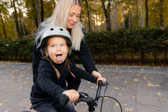 Happy moments of life, lifestyle of fatherhood. Mom and daughter learning with ride on bicycle for teaching at outdoor park with sunlight.
