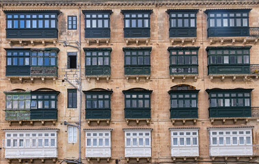 Architectural background of a historic limestone building facade with rows of traditional enclosed...
