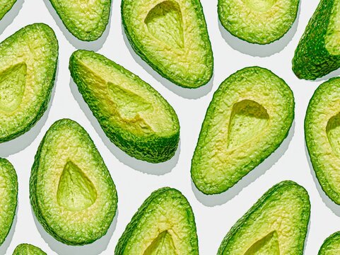 Avocado halves arranged in a repeating pattern on a white background