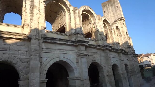 Close view of the ancient Roman Theatre of Arles, featuring monumental stone arches and columns under a clear blue sky in Provence, France.