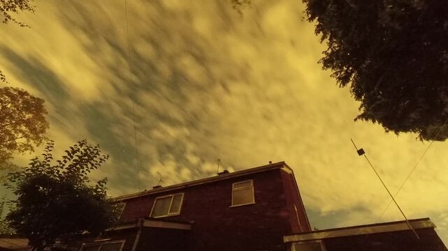 Fast moving night sky stars and clouds above English home property with flashing lights
