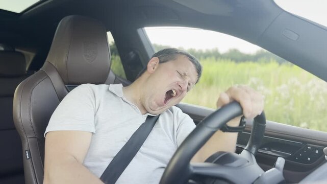 Tired man yawning and falling asleep while driving a car, showing drowsy driving and road safety risk