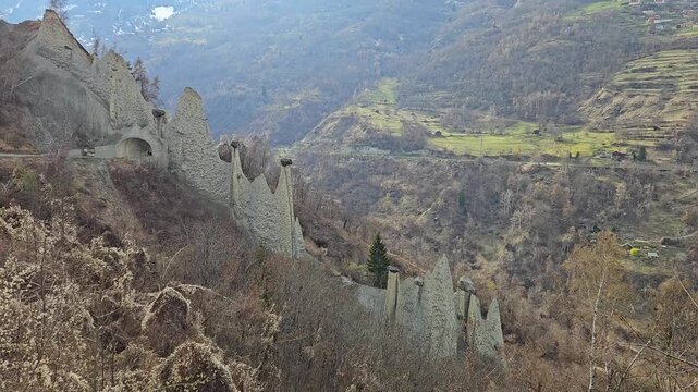 A wide shot of the unique Pyramides dEuseigne earth pyramids and rock formations in the Swiss Alps. Suitable for travel documentaries and geological studies.