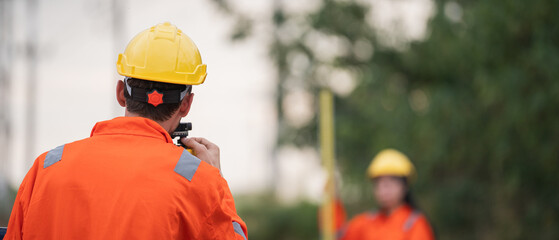 Civil engineers and survey team using a total station theodolite and road construction plans to...