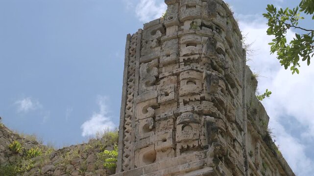 Static low angle shot of carved Chaac god masks on the stone corner of an ancient Mayan temple at Uxmal archaeological site in Yucatan, Mexico.