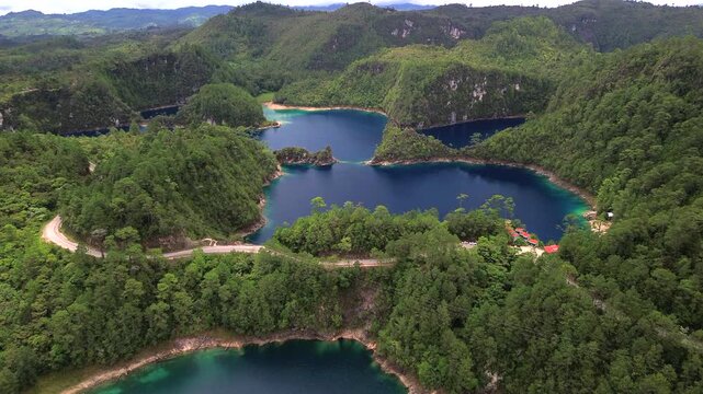Aerial shot pushing forward over turquoise lakes surrounded by dense pine forest at Lagunas de Montebello National Park in Chiapas, Mexico.