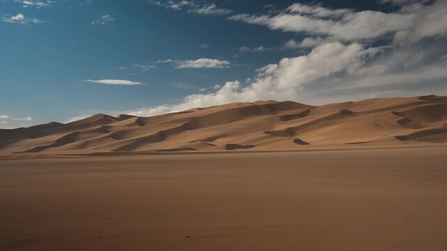 Vast rolling sand dunes beneath dramatic clouds and expansive desert skies, establishing panoramic pan right in lowlands