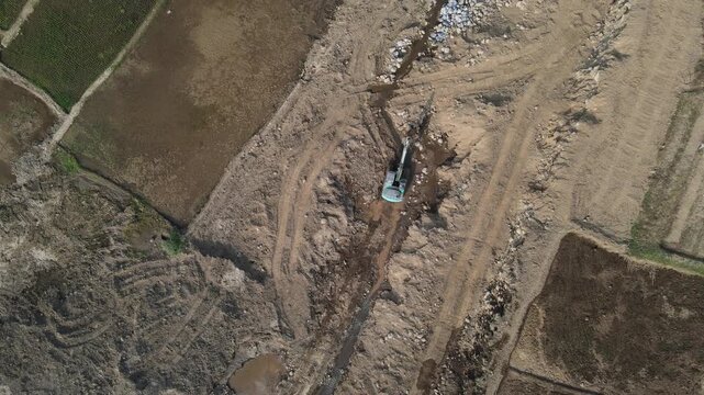 Aerial Footage of Mining Work in a Large-Scale Rock and Sand Quarry, Excavator Operating in Muddy and Wetland Mining Area. Highlights Heavy Machinery Working Through Waterlogged Terrain.