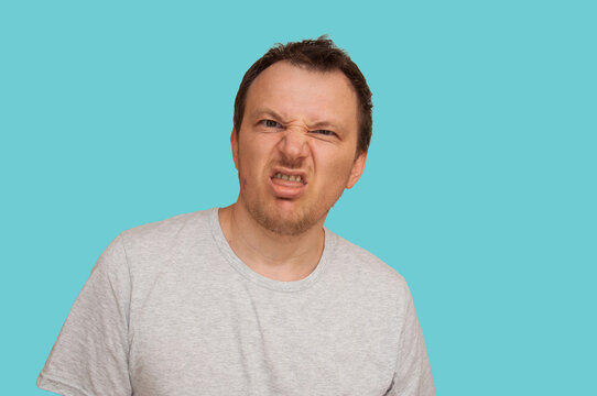 Man grimacing with disgust and disbelief against a bright blue background