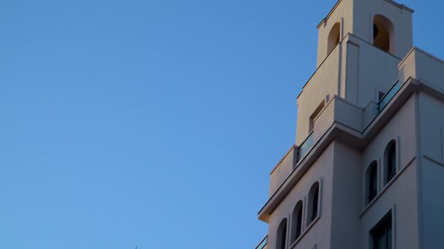 Low angle shot of a contemporary building facade and tower in Madrid, Spain. Suitable for travel documentaries, urban development, and real estate marketing.