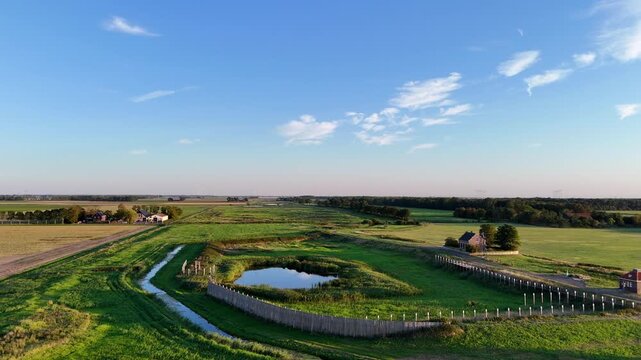 A scenic drone shot capturing the historic former island of Schokland in the Netherlands on a bright, sunny day. Rotating show of former harbour and lighthouse.