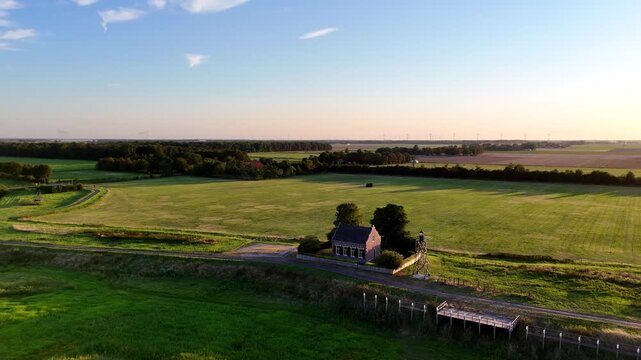 A scenic drone shot capturing the historic former island of Schokland in the Netherlands on a bright, sunny day. Rotating shot of Lighthouse en foghorn house with former harbor.