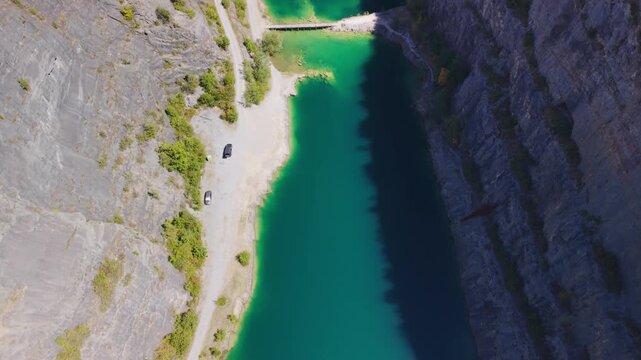 High aerial top-down view of turquoise flooded limestone lake and bridge at Velka Amerika quarry, Cesky Kras, Czech Republic