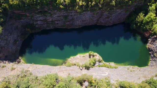 Directly overhead top-down aerial view of emerald water and limestone rock walls at Mala Amerika quarry, Cesky Kras, Czech Republic