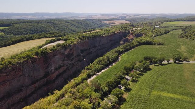 Drone orbit shot circling above emerald flooded lake and steep canyon rock walls at Velka Amerika limestone quarry, Cesky Kras, Czech Republic