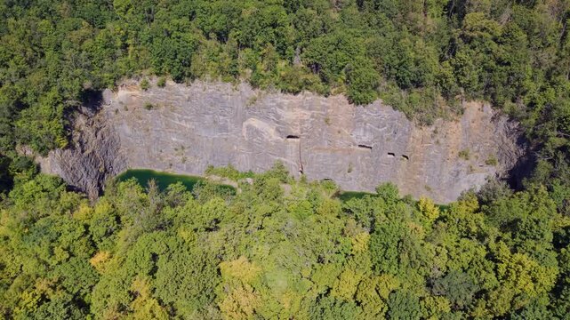 Drone orbit shot around Mala Amerika flooded limestone quarry with emerald water and steep cliffs, Cesky Kras, Czech Republic